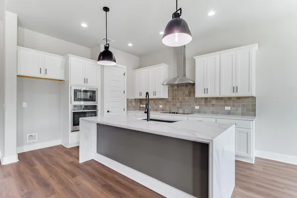 a kitchen with stainless steel appliances granite countertop a sink a stove a refrigerator and island with wooden floor