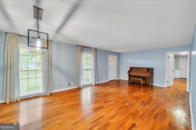 a view of a livingroom with furniture wooden floor a chandelier and windows