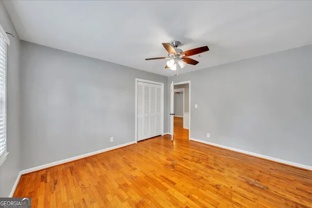 a view of a big room with wooden floor and a chandelier fan