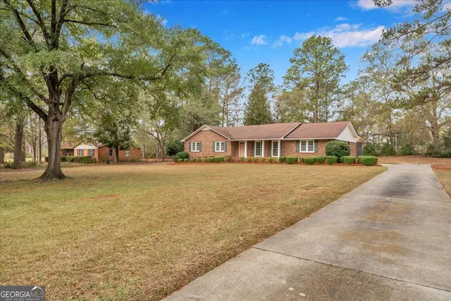 a front view of a house with large trees