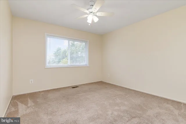 an empty room with a window and a fan