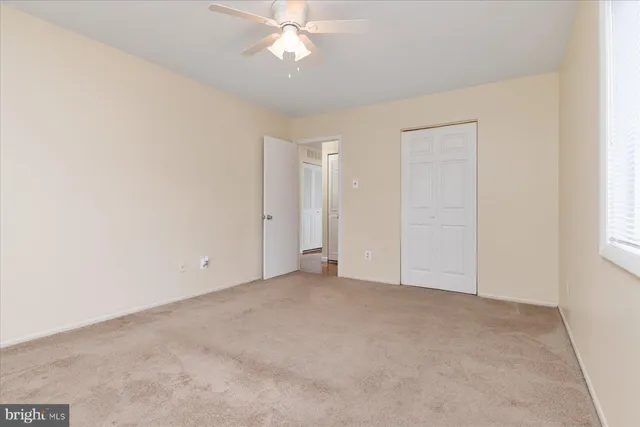 an empty room with a chandelier fan and windows