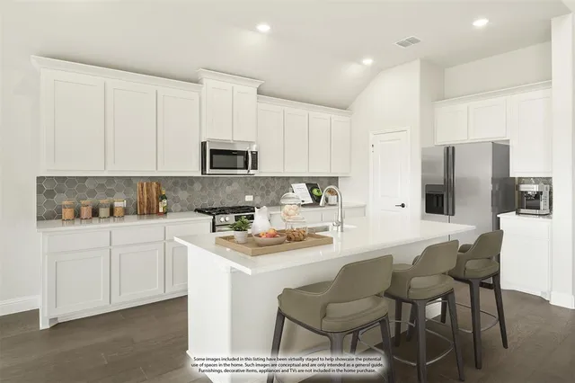 a kitchen with stainless steel appliances granite countertop a stove a sink a microwave a refrigerator and white cabinets