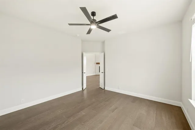 an empty room with wooden floor and ceiling fan