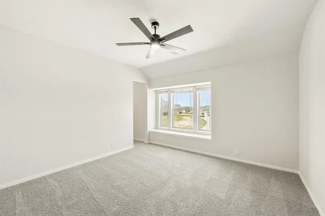 an empty room with ceiling fan and window
