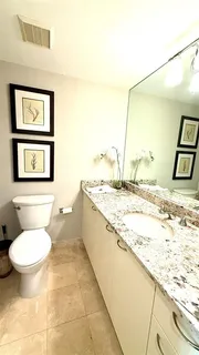 a bathroom with a granite countertop toilet a sink and a large mirror
