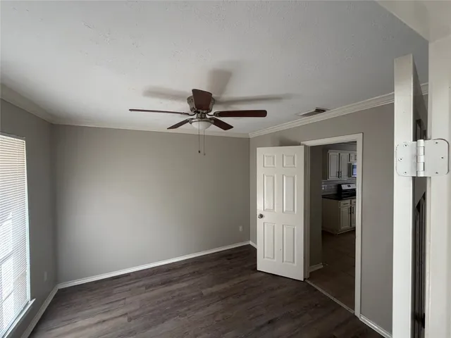 an empty room with wooden floor closet and windows