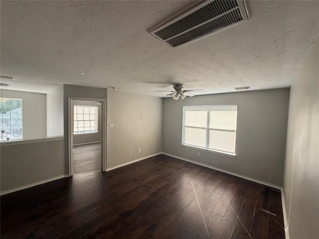 an empty room with wooden floor and windows