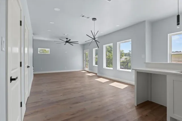 a view of an empty room with a window and wooden floor