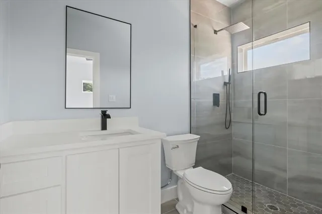 a bathroom with a toilet sink vanity and shower