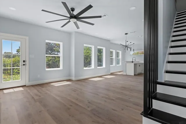 an empty room with wooden floor fan and windows