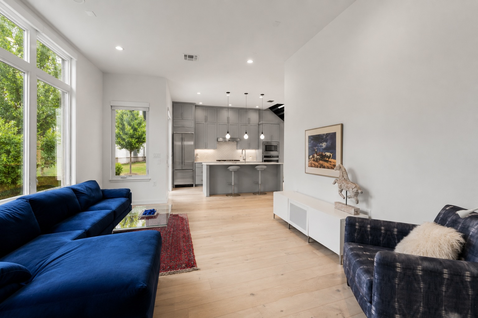 2520 Sutherland Street Austin, TX 78746 - Photo 9 of 26 Natural light floods this open-concept interior, highlighting the bright wood flooring.
