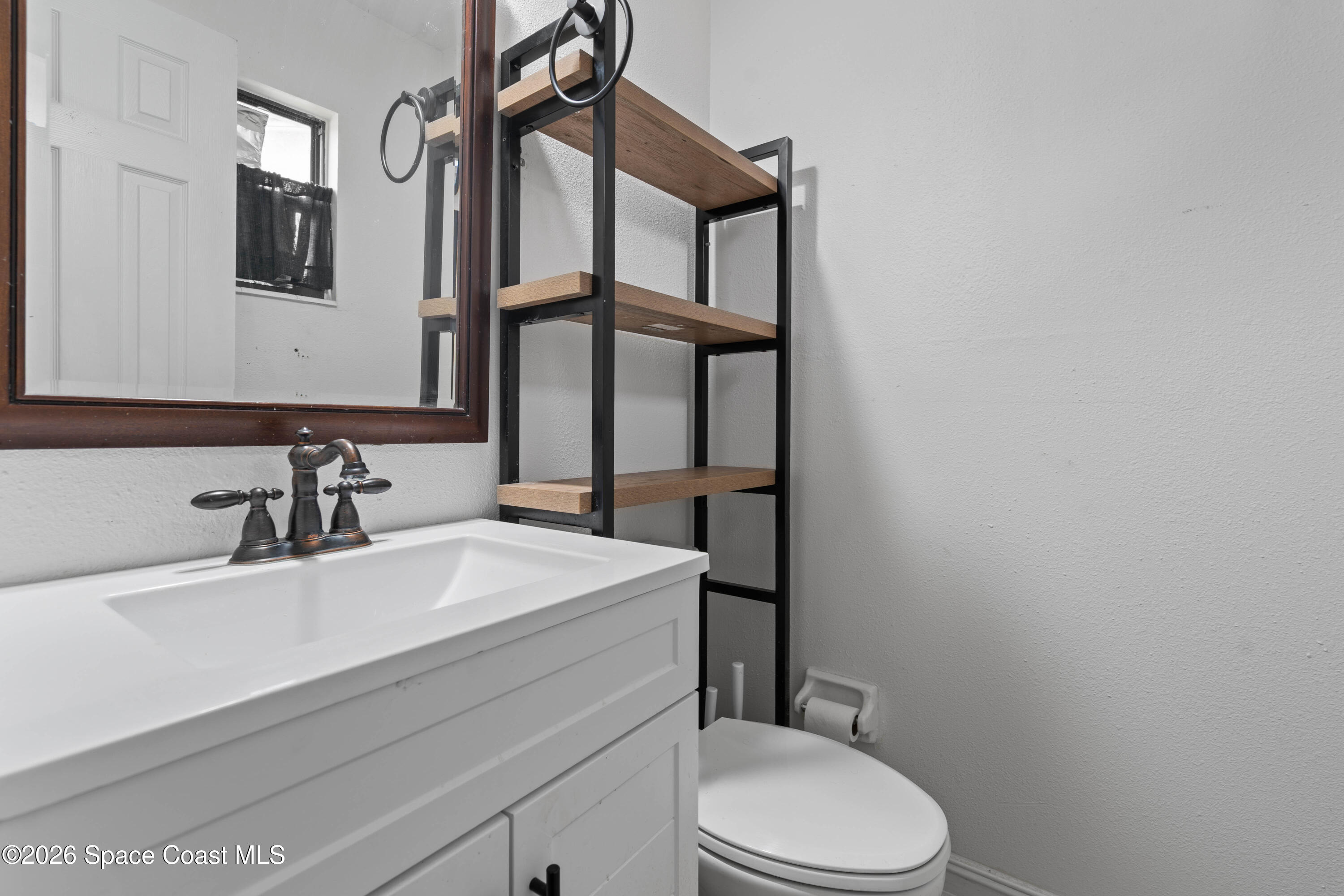 4037 Edwards Street Melbourne, FL 32901 - Photo 15 of 20 a bathroom with a sink a toilet and mirror