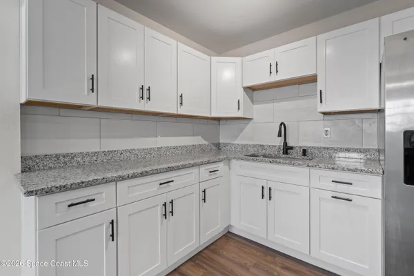 a kitchen with granite countertop white cabinets and a sink