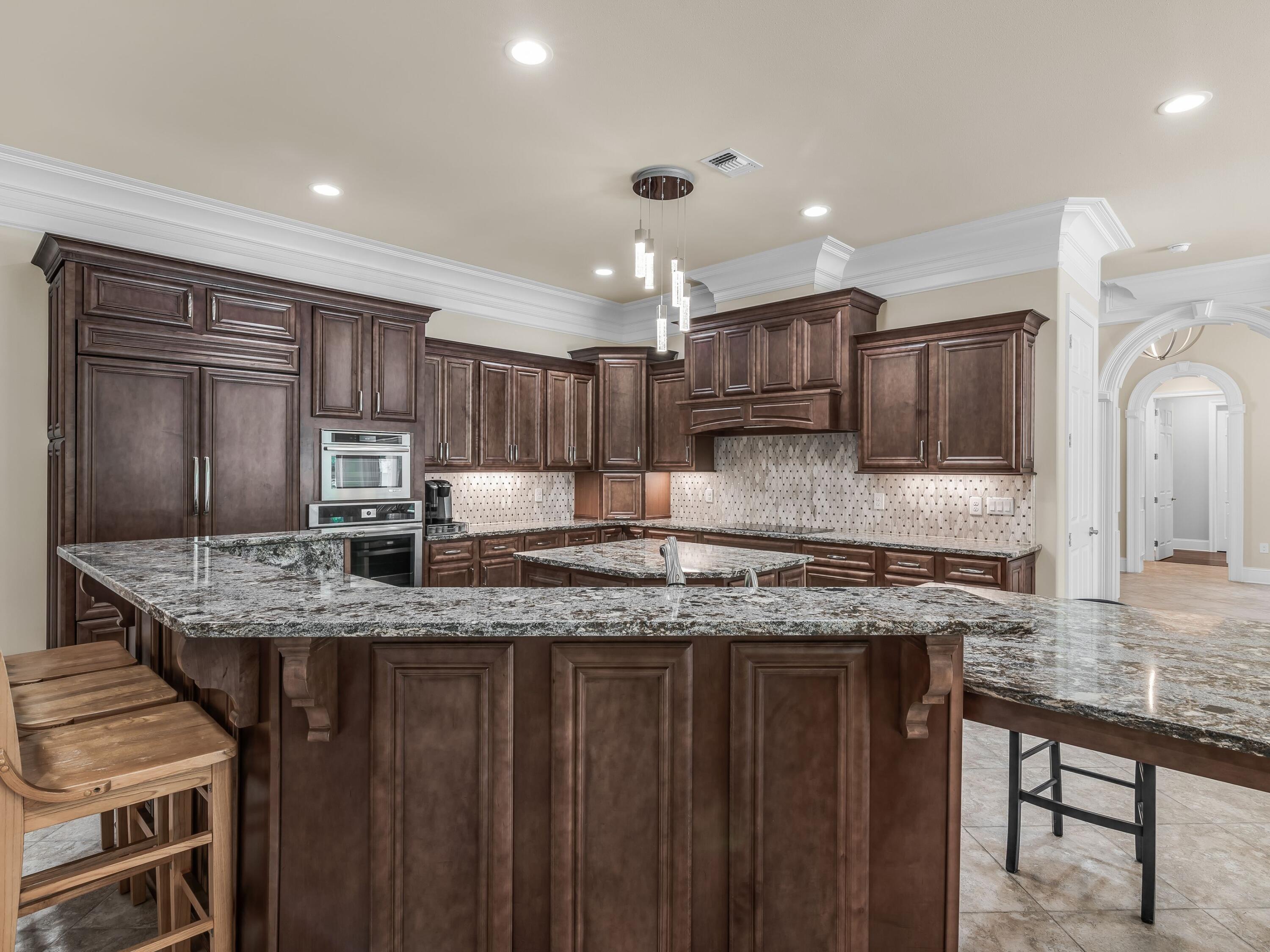 2916 Pine Valley Drive Sandestin, FL 32550 - Photo 20 of 48 a kitchen with kitchen island granite countertop wooden cabinets stools a sink stainless steel appliances and a counter space