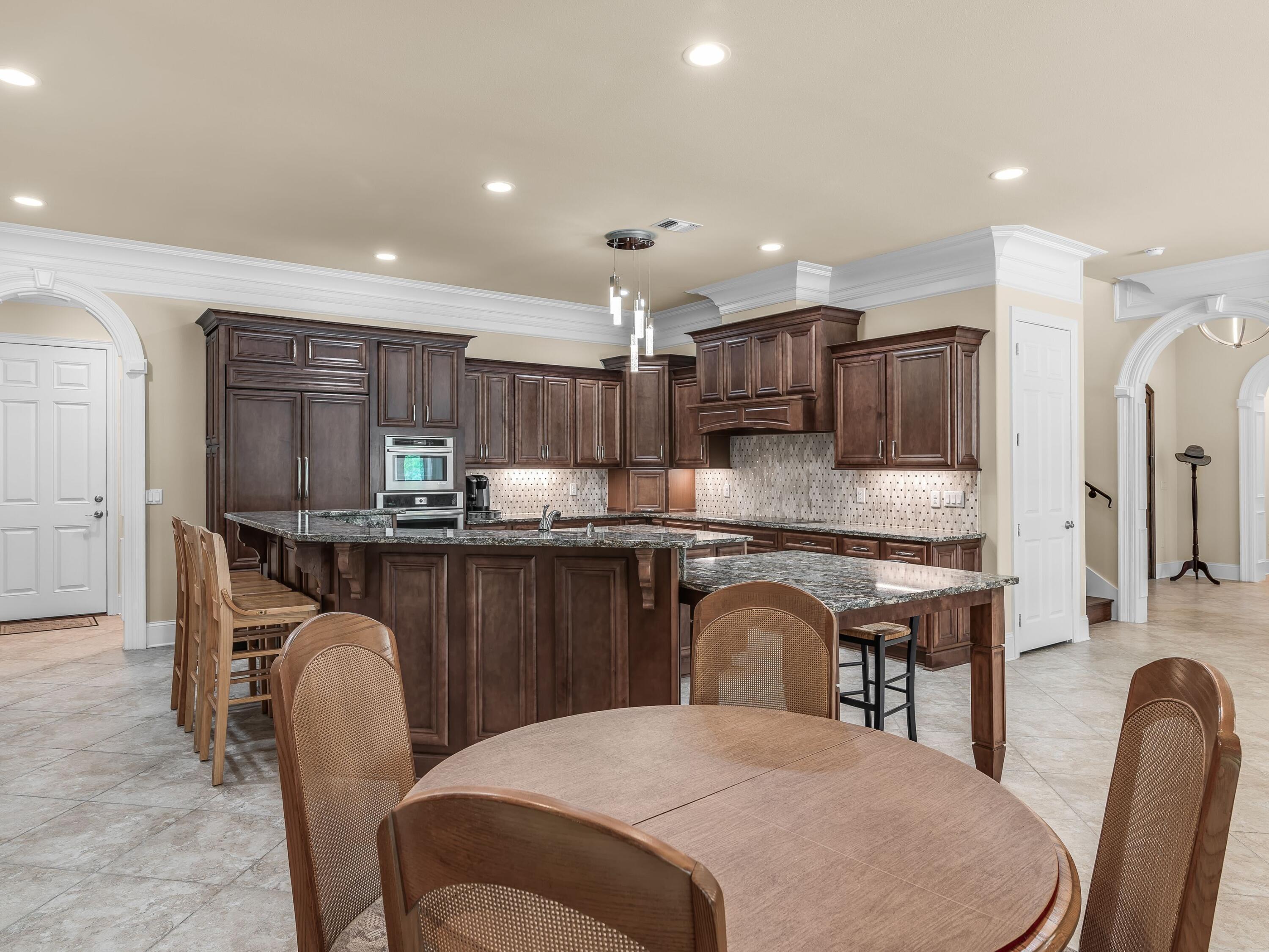 2916 Pine Valley Drive Sandestin, FL 32550 - Photo 21 of 48 a kitchen with kitchen island a dining table chairs cabinets a sink and appliances