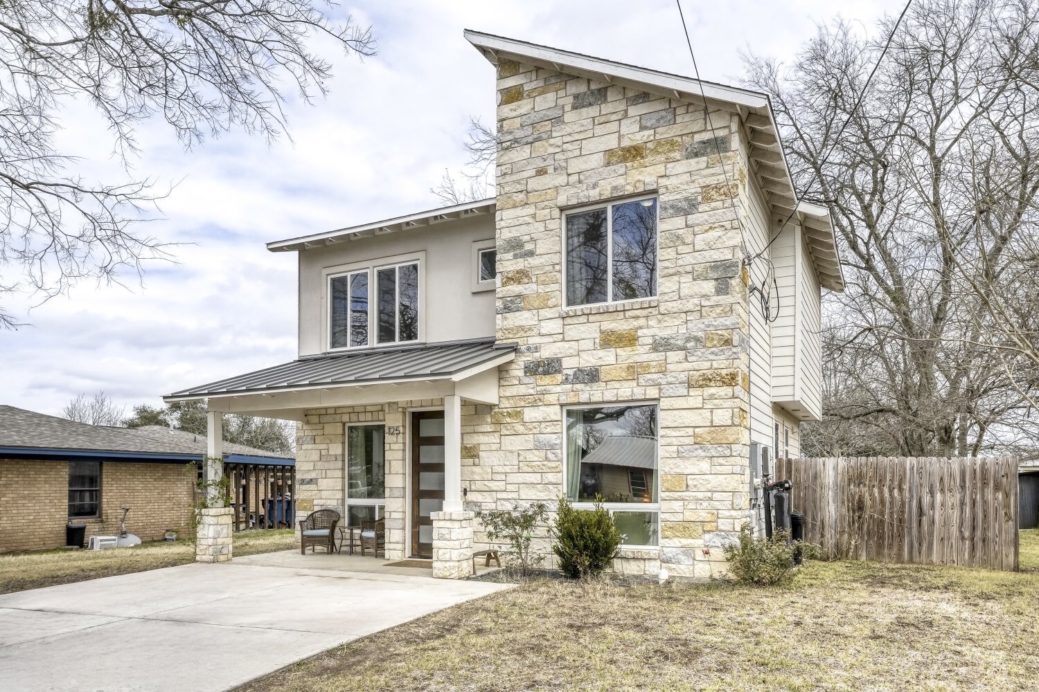 125 Irene Street Elgin, TX 78621 - Photo 2 of 24 Modern home featuring stone siding, a standing seam roof, and a porch