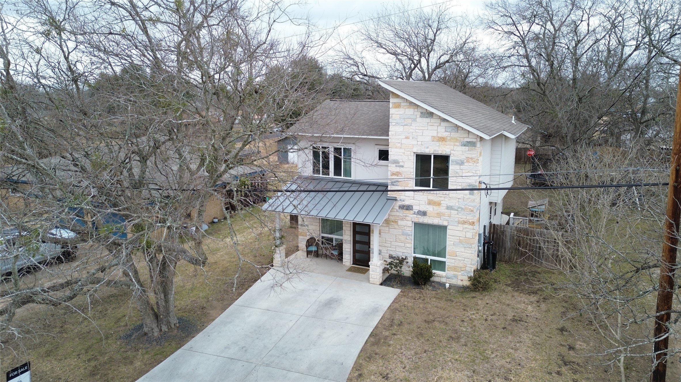 125 Irene Street Elgin, TX 78621 - Photo 22 of 24 View of front of property with stone siding, driveway, a standing seam roof, and roof with shingles
