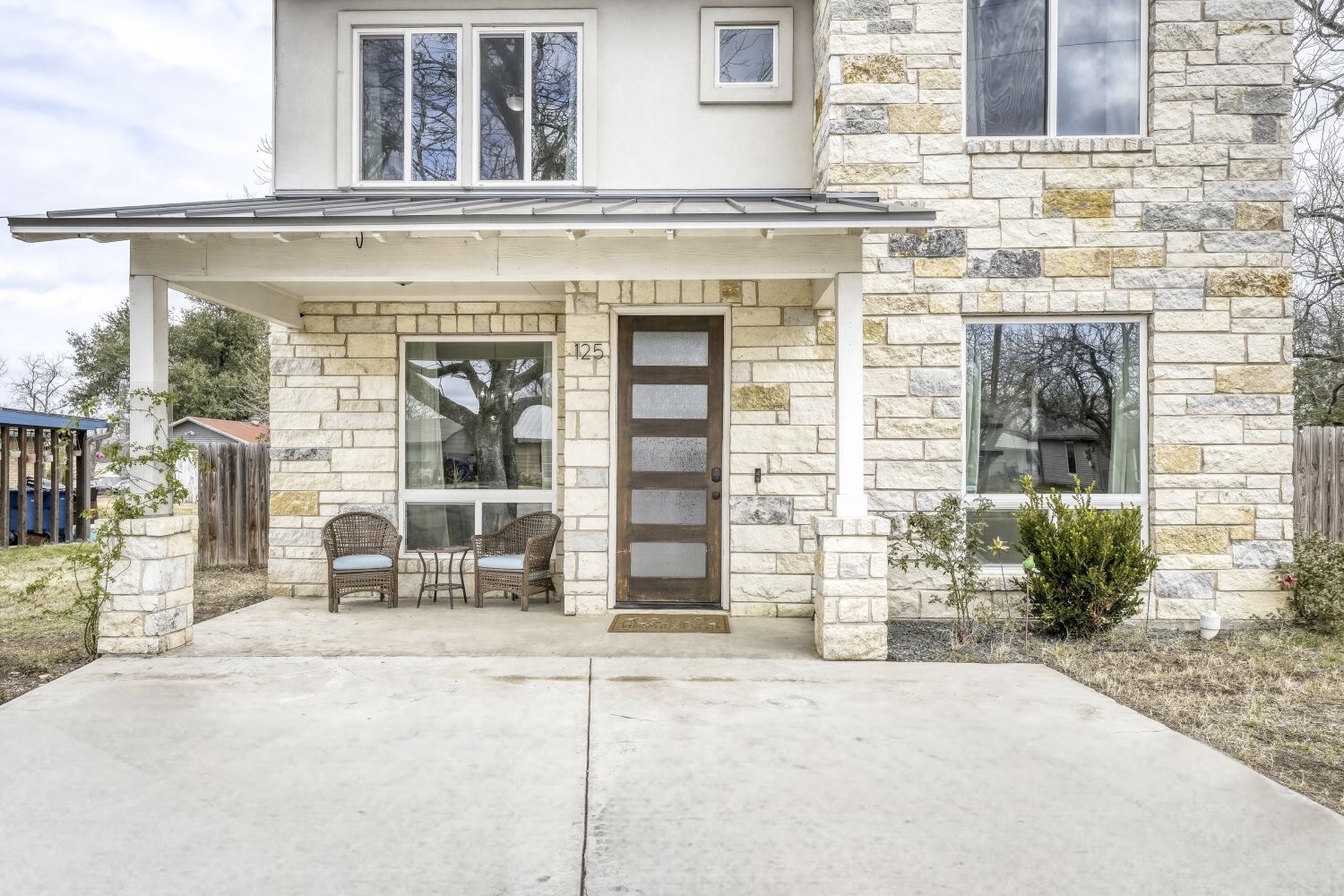 125 Irene Street Elgin, TX 78621 - Photo 3 of 24 Doorway to property with stone siding, a standing seam roof, and a patio area