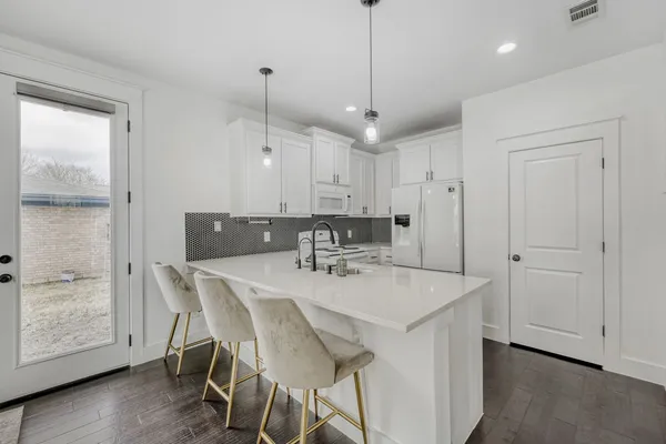 a view of a dining room and a kitchen with a table chairs