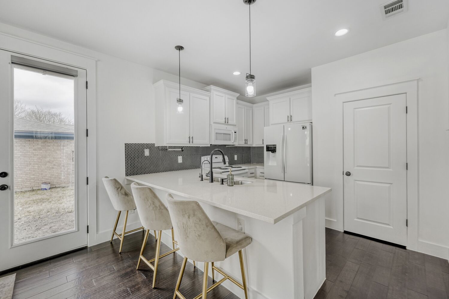 125 Irene Street Elgin, TX 78621 - Photo 10 of 24 Kitchen featuring white cabinetry, white appliances, a peninsula, a kitchen breakfast bar, and pendant lighting