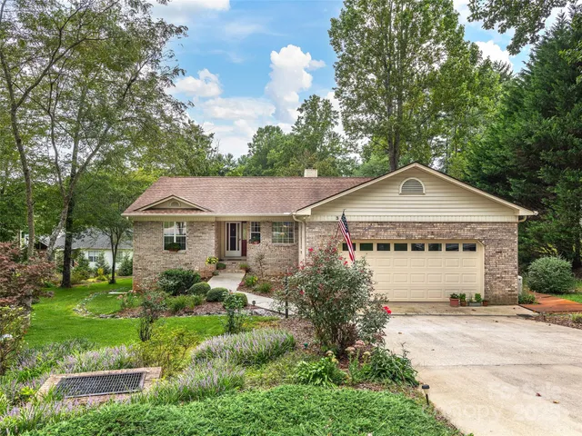 a view of a house with a yard plants and large tree