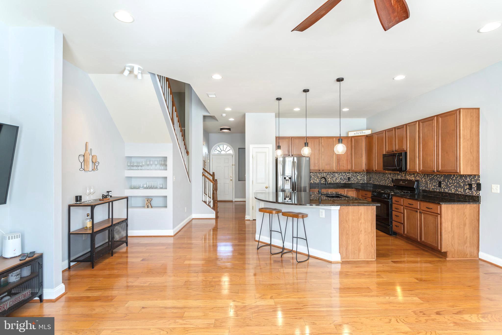 9152 Ribbon Falls Loop Bristow, VA 20136 - Photo 20 of 61 a kitchen with stainless steel appliances kitchen island granite countertop a table chairs and a refrigerator
