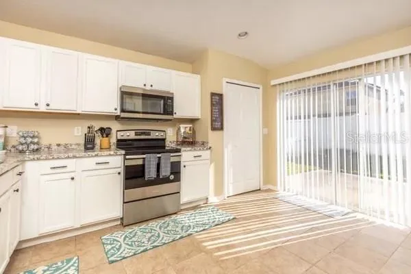 a kitchen with granite countertop a stove top oven and cabinets