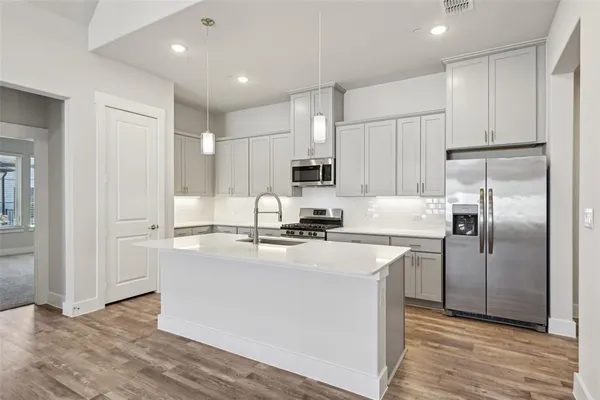 a kitchen with stainless steel appliances granite countertop a refrigerator sink and white cabinets