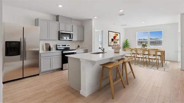a kitchen with stainless steel appliances granite countertop a table chairs microwave and sink