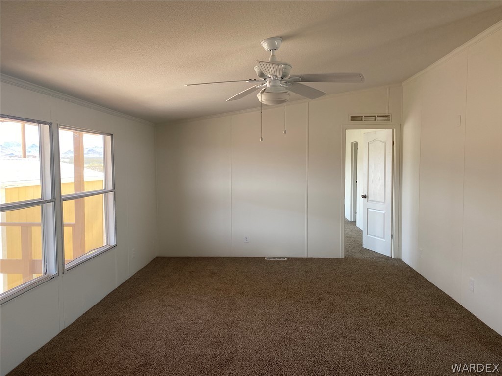 4568 Eden Road Golden Valley, AZ 86413 - Photo 9 of 25 en empty room with windows and chandelier fan