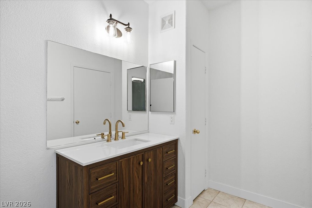 9050 West Warm Springs Road, Unit 1033 Las Vegas, NV 89148 - Photo 13 of 26 Modern vanity with dual gold faucets and expansive mirror creates a chic, functional space.