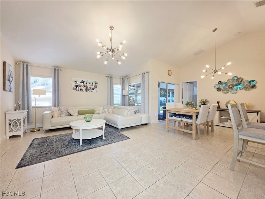 a living room with furniture dining table a chandelier a rug and a window