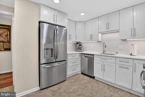 a kitchen with white cabinets stainless steel appliances and a refrigerator