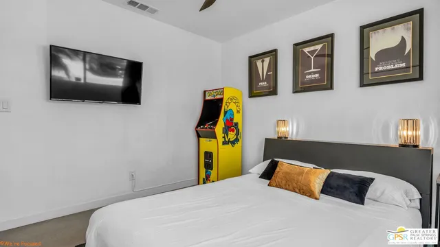 a bedroom with a bed television on desk and a window