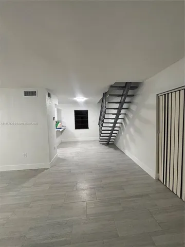 a view of an empty room with stairs and a window