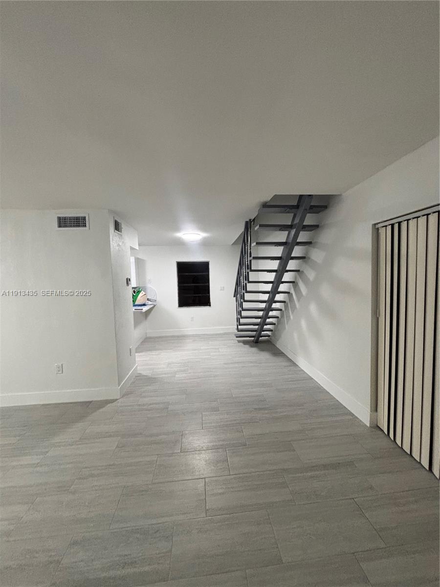 1799 Southwest 36th Avenue, Unit 1 Miami, FL 33145 - Photo 4 of 14 a view of an empty room with stairs and a window