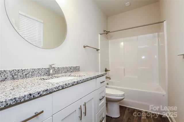 a bathroom with a granite countertop sink a toilet and shower