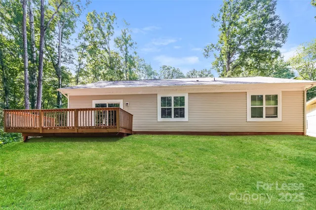 a view of a house with a yard and a large tree