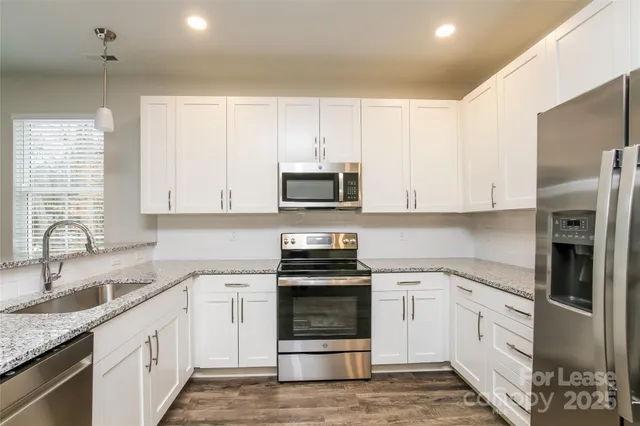 a kitchen with granite countertop white cabinets and stainless steel appliances
