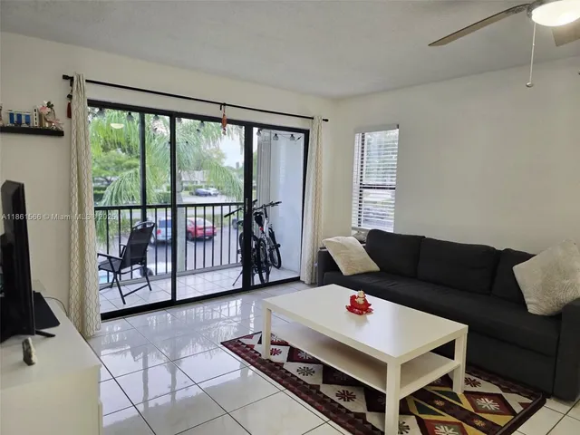 a living room with furniture a flat screen tv and a floor to ceiling window