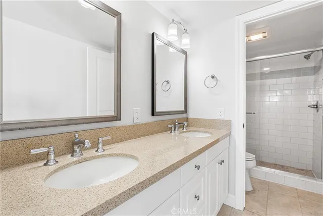a bathroom with a granite countertop double vanity sink shower and a mirror