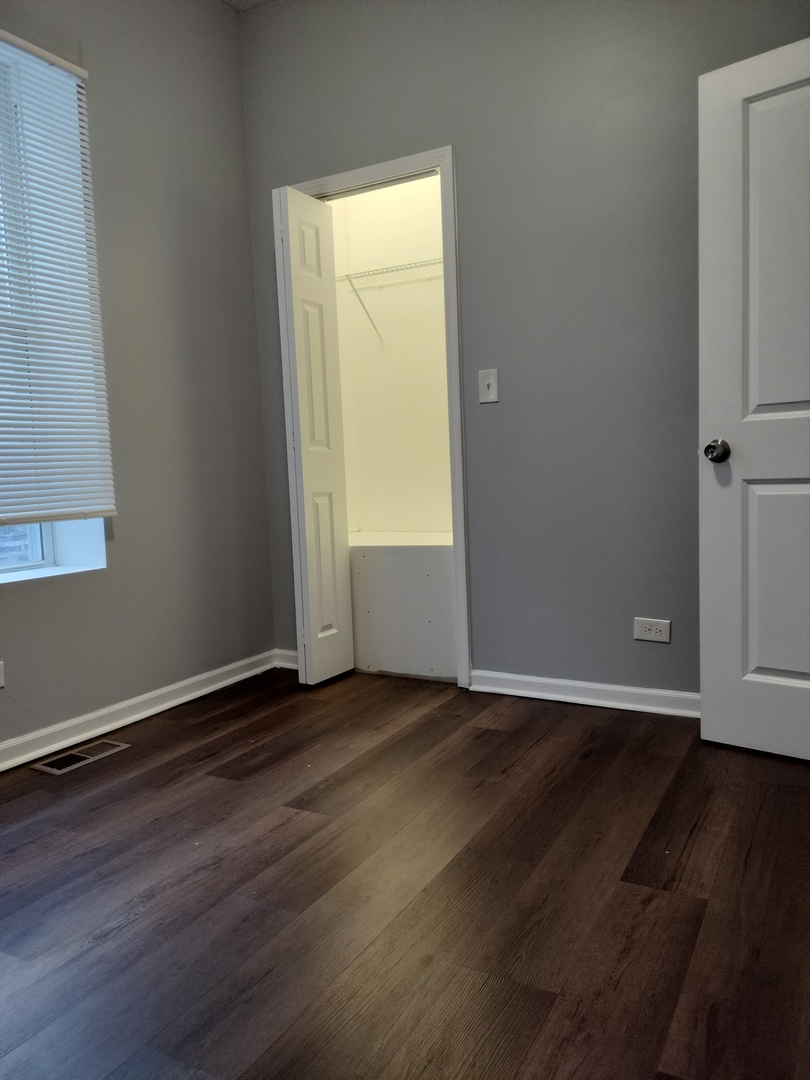 5725 South Green Street, Unit 1 Chicago, IL 60621 - Photo 12 of 18 an empty room with wooden floor and windows