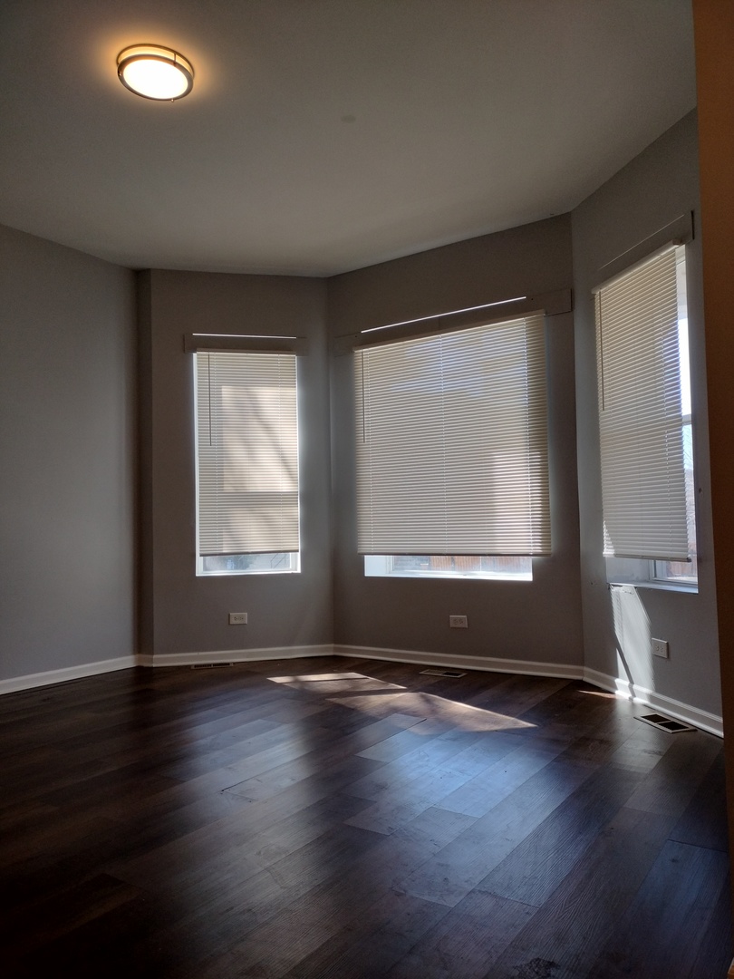 5725 South Green Street, Unit 1 Chicago, IL 60621 - Photo 3 of 18 an empty room with wooden floor and windows