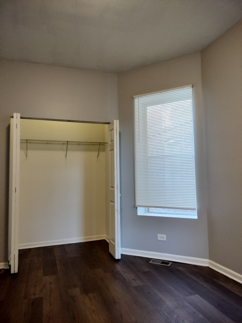 5725 South Green Street, Unit 1 Chicago, IL 60621 - Photo 8 of 18 an empty room with wooden floor and closet