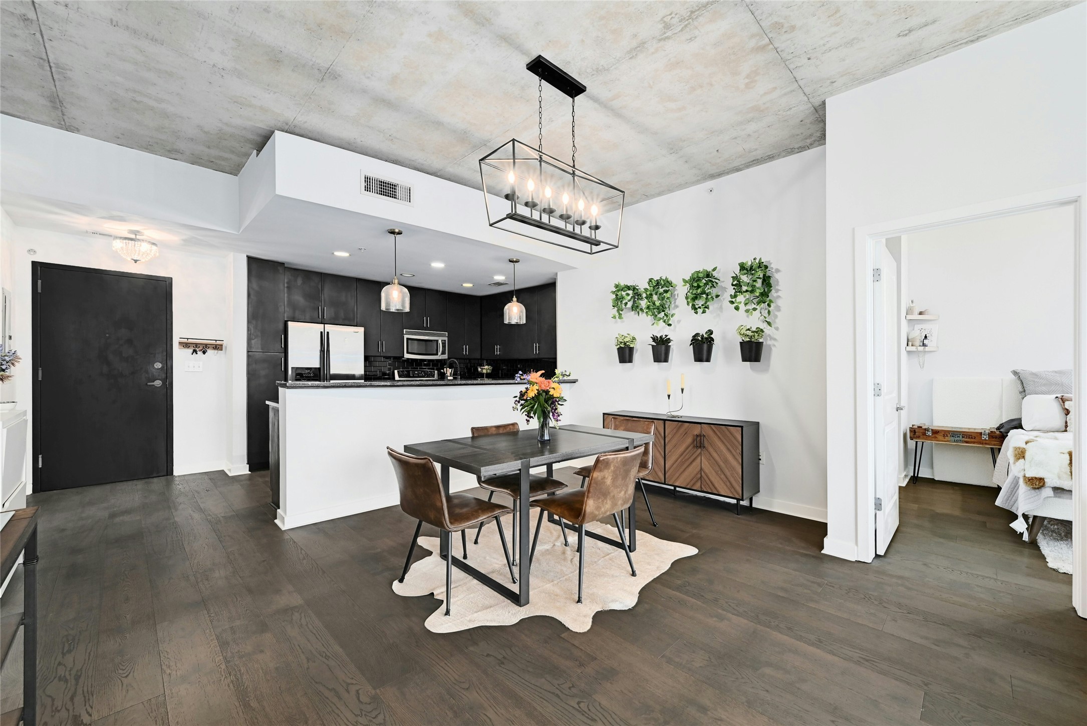 360 Nueces Street, Unit 1809 Austin, TX 78701 - Photo 7 of 25 Open-concept living area featuring wide-plank wood-finish flooring, a concrete ceiling, and a kitchen with dark cabinetry and a breakfast bar