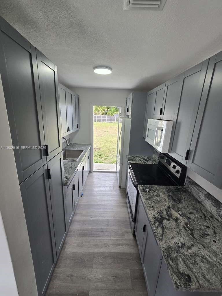 26633 Southwest 138th Court, Unit 1 Homestead, FL 33032 - Photo 2 of 8 a kitchen with granite countertop a sink stove and refrigerator
