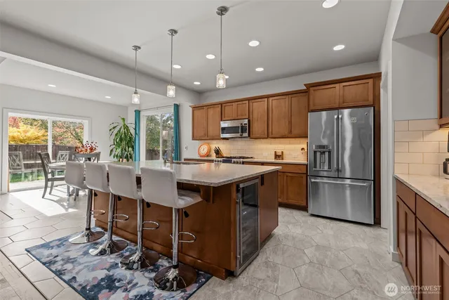 a kitchen with kitchen island granite countertop a table chairs microwave and refrigerator