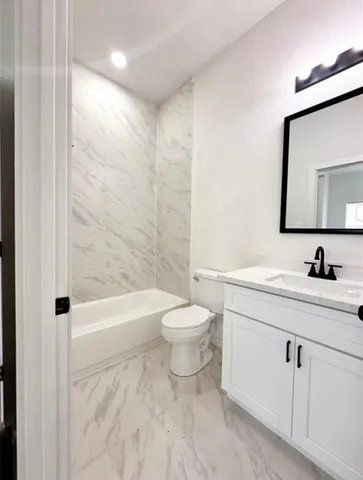 a bathroom with a granite countertop sink a toilet and shower