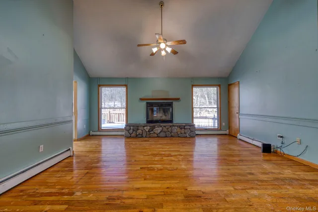 a view of an empty room with window and chandelier fan